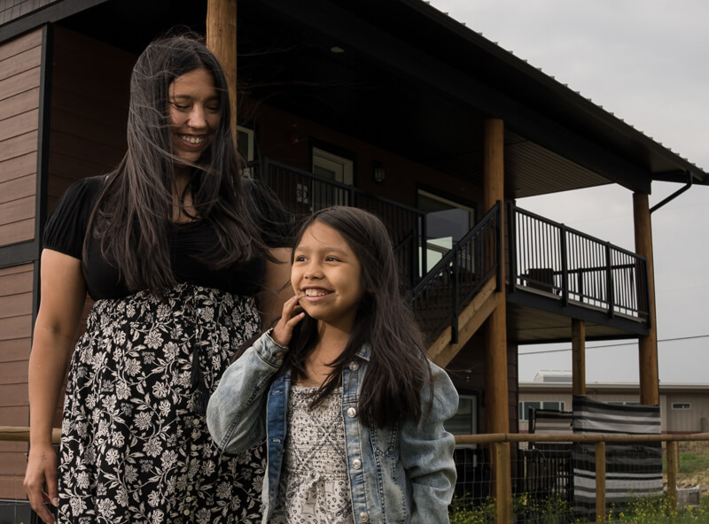 Lauren Marchand smiles down at her smiling daughter outside their house.